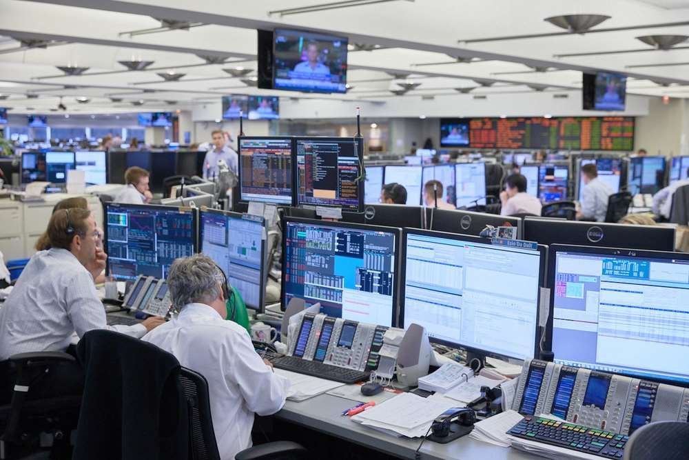 Institutional trading floor with multiple screens showing financial markets and forex activity